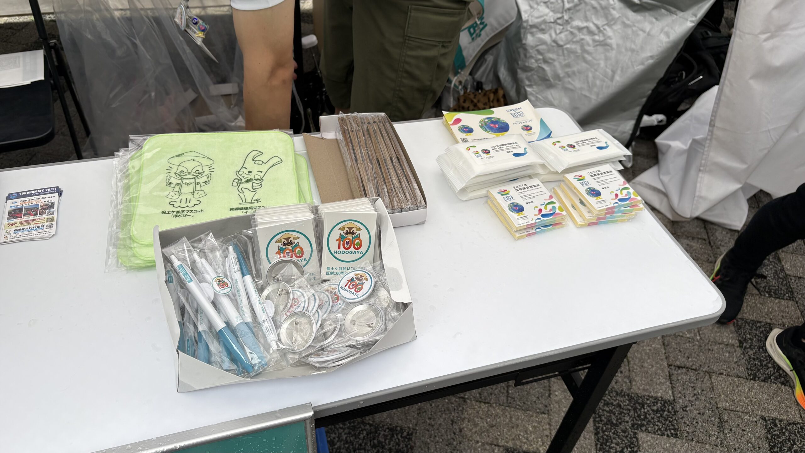 保土ケ谷区グッズとGREEN×EXPO 2027グッズが並ぶテーブル