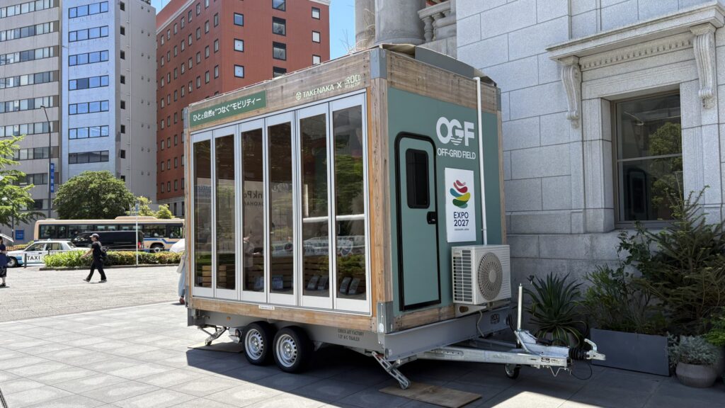 OFF-GRID FIELDとEXPO 2027のロゴが入ったトレーラー。側面はガラス張り