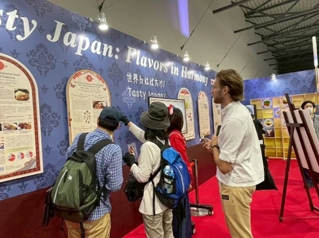 大阪・関西万博の展示「世界にはばたけ!Tasty Japan!」のブースを見る来場者