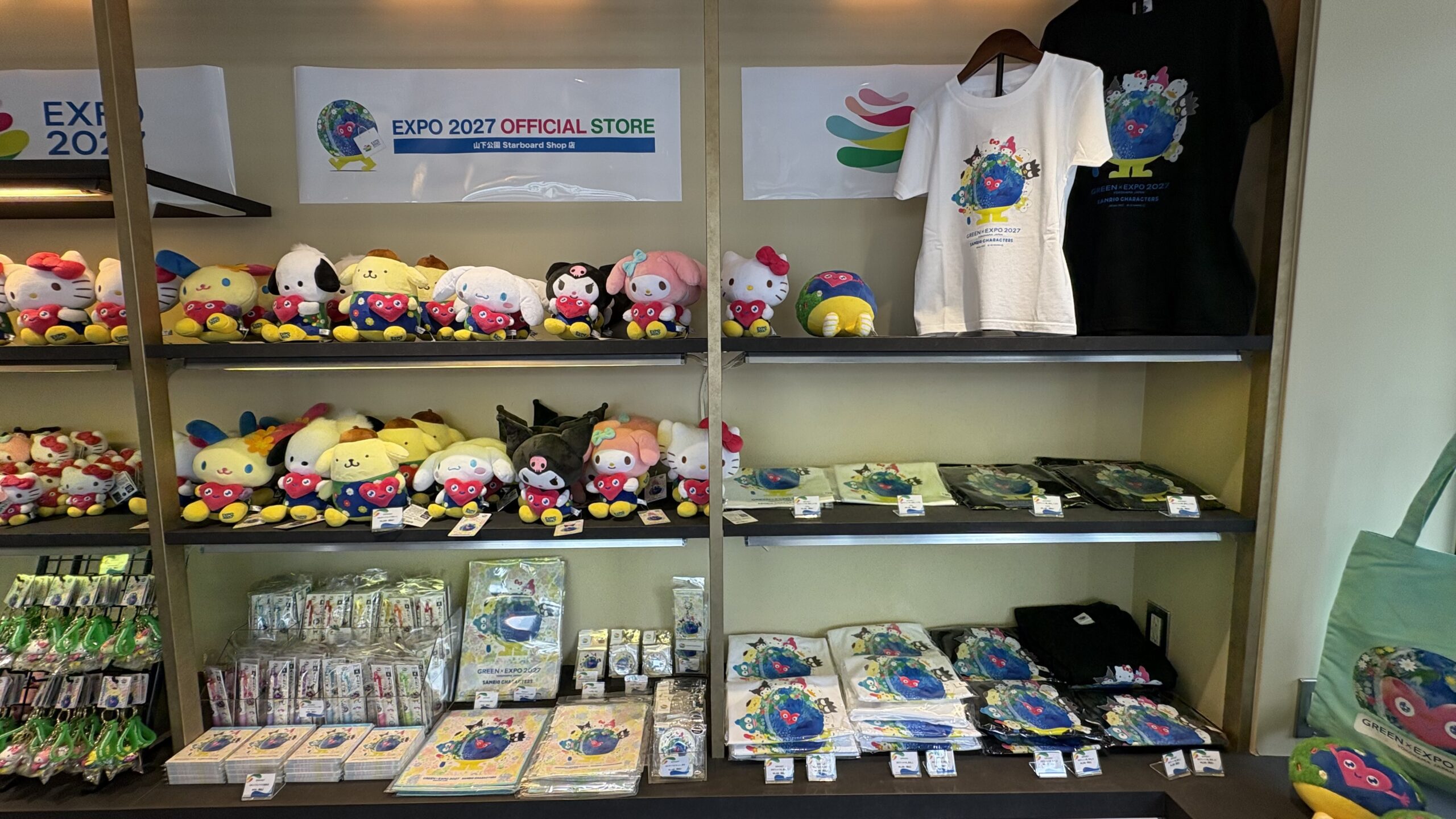 棚の上段に店名の掲示。サンリオコラボのぬいぐるみとTシャツが並びます