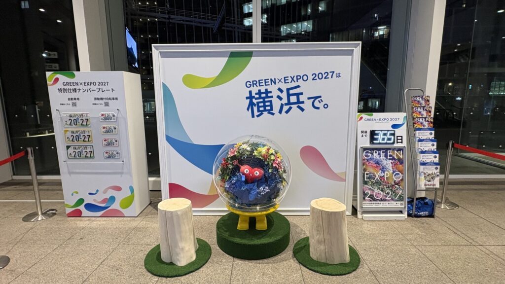 横浜市役所1階アトリウムに展示されたGREEN×EXPO 2027特別仕様ナンバープレートとトゥンクトゥンクのモニュメント
