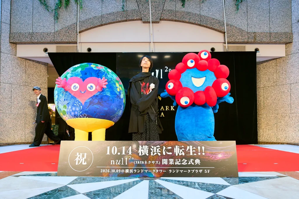 「10.14 横浜に転生!!」の看板の前に並ぶトゥンクトゥンク、落合陽一さん、ミャクミャク