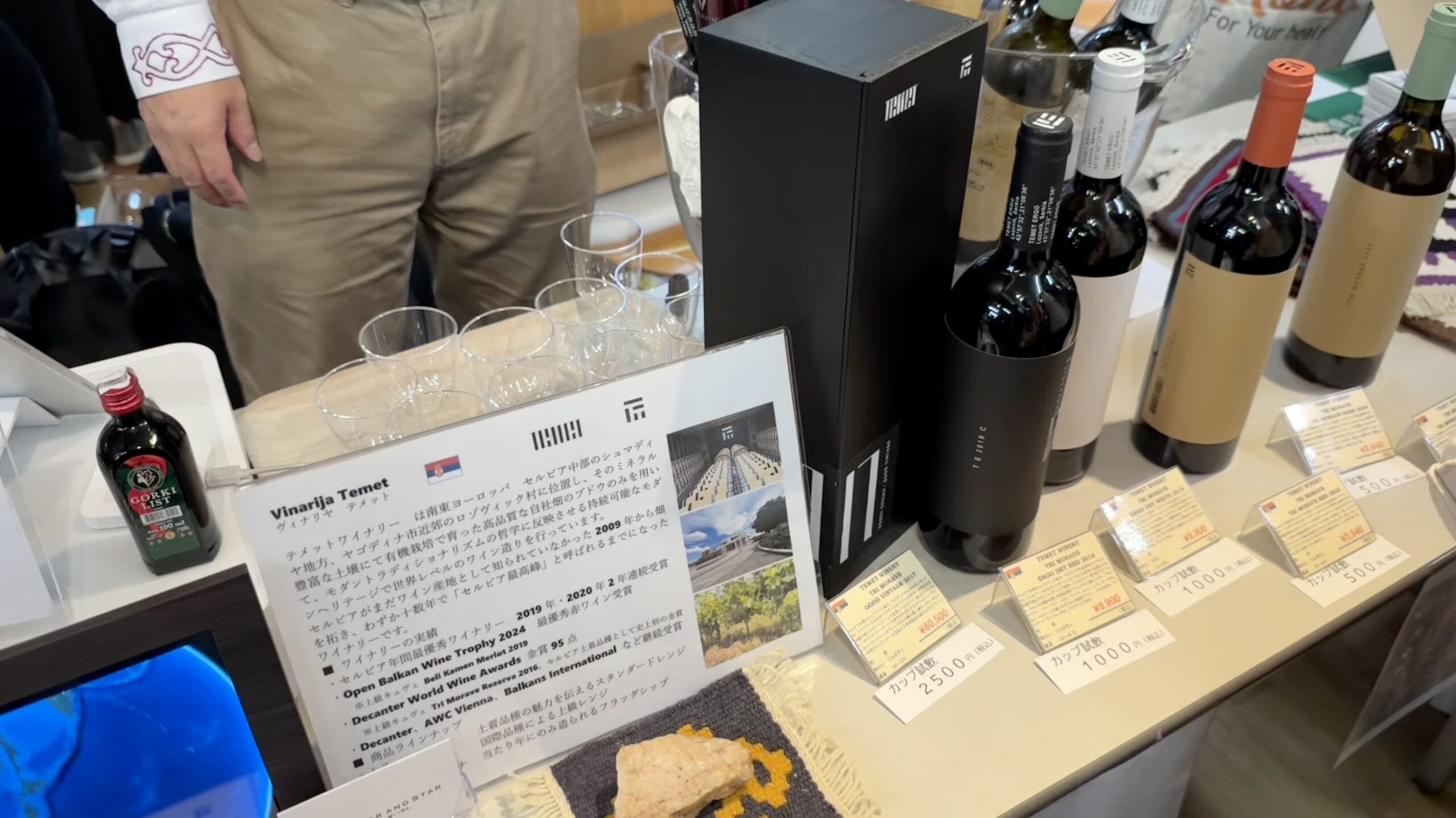 ワインのブース。ボトルとカップ試飲の価格札