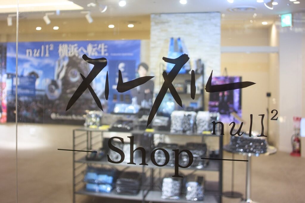 ガラスに「ﾇﾙﾇﾙ null² Shop」のロゴ。奥にTシャツなどのグッズが並ぶ