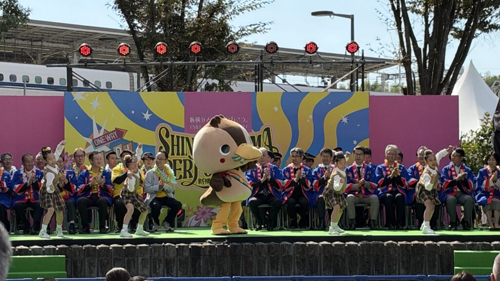 ステージ中央でポーズをとるかもねくんとチアリーディングの子どもたち