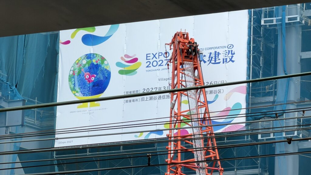 工事現場の清水建設の看板。EXPO 2027のロゴとトゥンクトゥンク、Village出展の文字