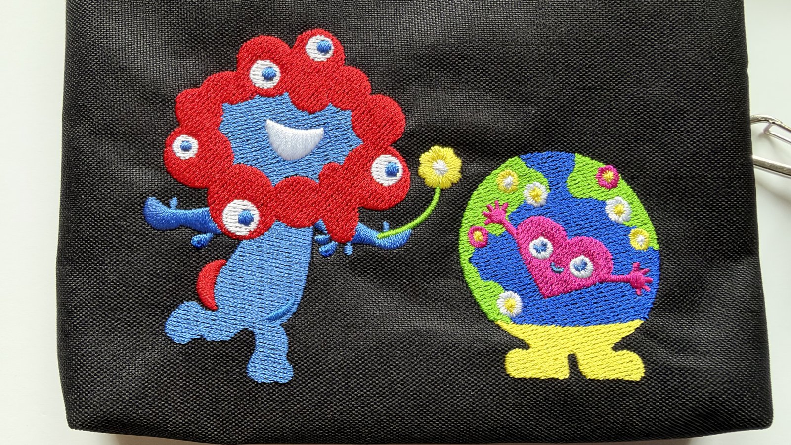 黒いスマホショルダーに刺繍されたミャクミャクとトゥンクトゥンク