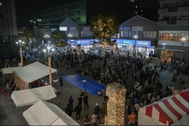 昨年度の点灯ミニイベント。夜の瀬谷駅北口駅前広場に人が集まり、木々がライトアップされている