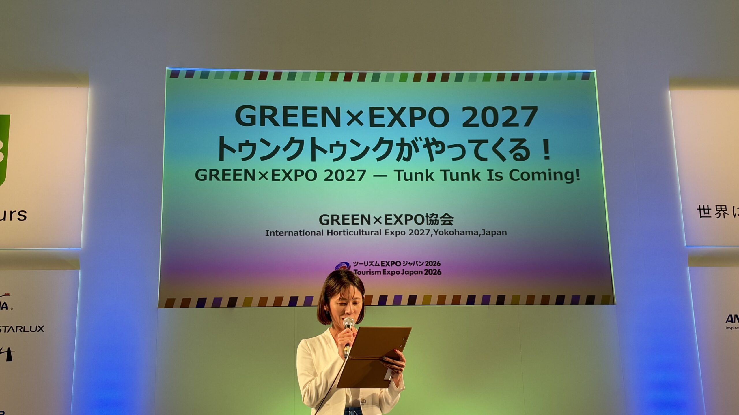 Bステージのスクリーンに映る「GREEN×EXPO 2027 トゥンクトゥンクがやってくる！」のタイトルと司会の女性