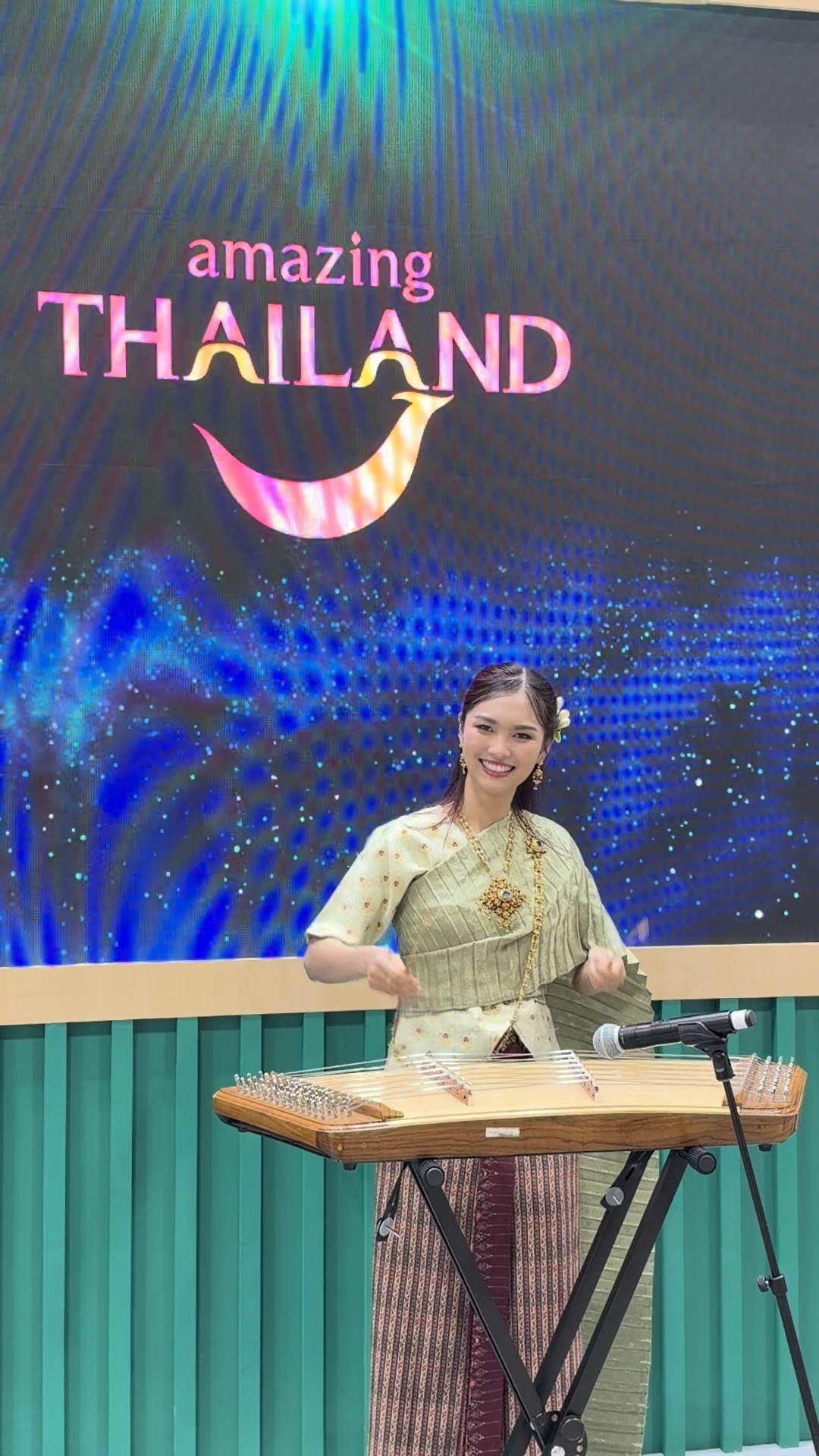 amazing THAILANDの映像の前で楽器を演奏する女性